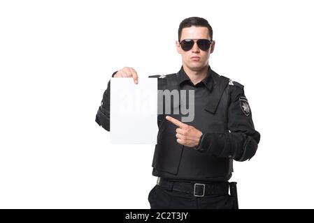 Seriuse Cop in Sonnenbrille Punkte in ein leeres Stück Papier, schwarze Uniform mit Schutzkleidung, weißen Hintergrund. Polizisten in spezielle Munition Stockfoto