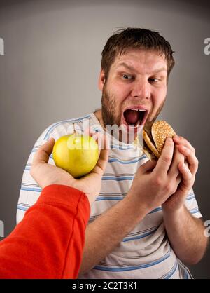 Porträt des Mannes, die Wahl zwischen Hamburger und grüner Apfel Stockfoto