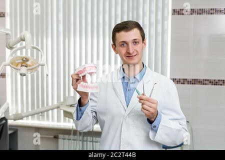 Junger Zahnarzt im Büro mit Instrumenten und künstlichem Kiefer Stockfoto