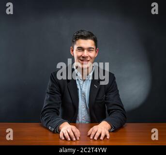 Lächelnder Geschäftsmann sitzt am Holztisch Stockfoto