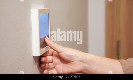 Junge Frau stellt Thermostat Tasten der Klimaanlage Panel an der Wand in komfortablen Hotel extreme Nahaufnahme Stockfoto