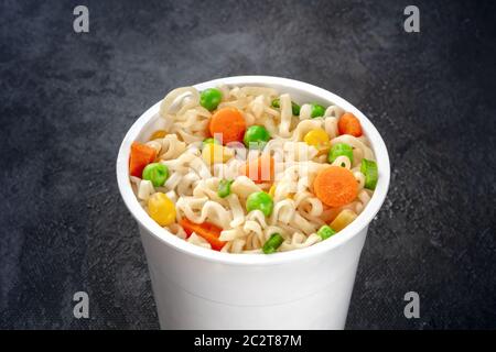 Ramen Schale, instant Soba-nudeln in einem Plastikbecher mit Gemüse close-up auf schwarzem Hintergrund Stockfoto
