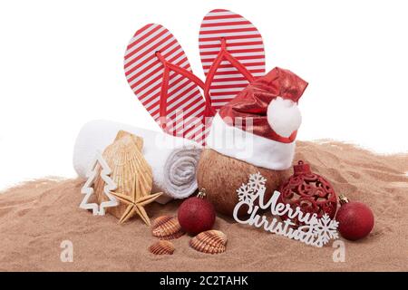 Stillleben mit Strandaccessoires (Flip Flops, Handtuch, Muscheln, Sand, Kokosnuss) und weihnachtsschmuck auf weißem Hintergrund. Weihnachten. Winterurlaub Stockfoto