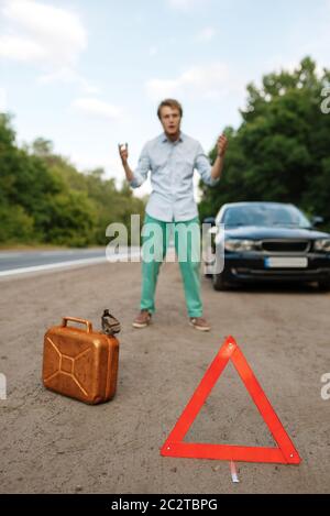 Notausfahrschild und Benzinkanister, Panne, Mann hatte kein Gas mehr. Zerbrochenes Auto oder Reparatur von Reifenpanne am Fahrzeug, Probleme mit Reifenpanne Stockfoto