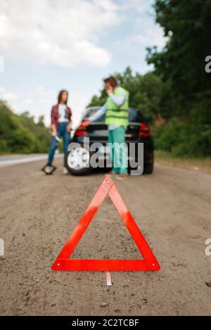 Not-aus-Schild, Pannendienst, Paar ruft für Abschleppwagen auf Hintergrund. Zerbrochenes Automobil oder Reparatur von Reifenpanne am Fahrzeug, Probleme mit p Stockfoto