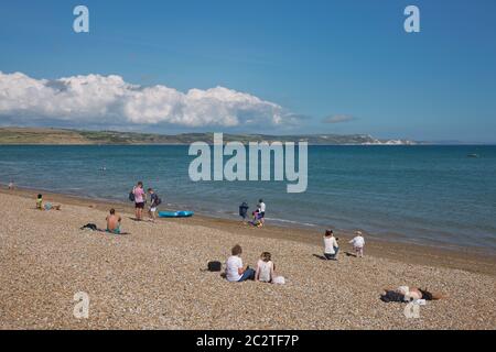 Menschen und Touristen genießen sonnigen Sommertag am Strand in Weymouth, Dorset, Großbritannien Stockfoto