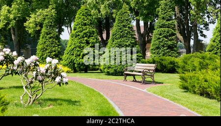 Bank im Park und gebogenen Stein Backstein Weg Stockfoto