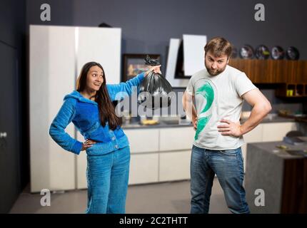 Frau bat ihren Mann, den Müll in der Küche zu nehmen Stockfoto