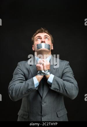 Mann mit Mund und Händen fallenden Klebeband verhindert Rede, isoliert auf schwarz Stockfoto
