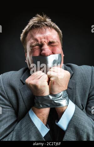 Mann mit Mund und Händen fallenden Klebeband verhindert Rede, Studio-Shooting Stockfoto