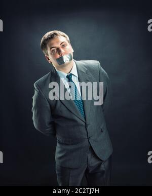 Mann mit Mund und Händen stehend fallenden Klebeband verhindert Rede, isoliert auf schwarz Stockfoto