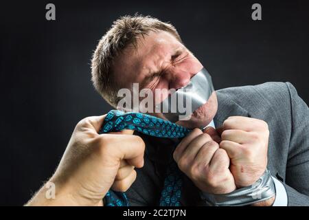 Mann im Aufnahmemodus mit Mund und Händen fallenden Klebeband verhindert Rede, isoliert auf schwarz Stockfoto