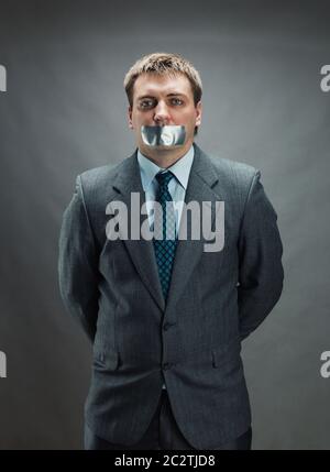 Mann mit Mund und Händen fallenden Klebeband verhindert Rede, isoliert auf grau Stockfoto