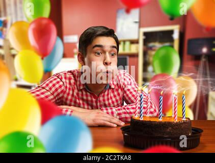 Geburtstagskind bläst Kerzen auf dem Kuchen in dekorierten Zimmer Stockfoto