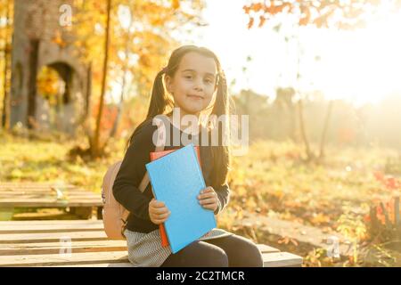 Weiter lernen. Kleines Kind genießt das Lernen im Herbstpark. Kinderstudium mit Buch. Kleines Mädchen lesen Buch am Herbsttag. Literaturkonzept Herbst. Klein Stockfoto