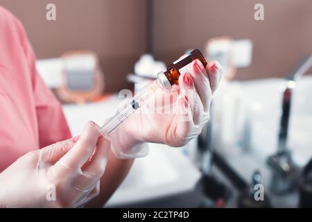 Arzt wählt Medizin in die Spritze aus Glasflasche, ein Arztpraxis im Hintergrund. Stockfoto