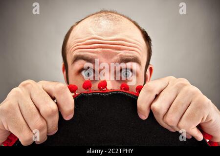 Sehr überrascht Mann versteckt sich hinter Sombrero-Hut Stockfoto