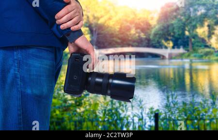 Männliche Kameramann Hände mit Digitalkamera, Closeup, grüne Natur und See im Hintergrund Stockfoto