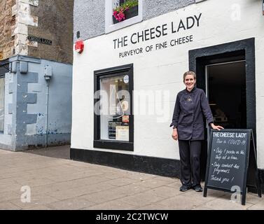 Haddington, East Lothian, Schottland, Großbritannien, 18. Juni 2020. Wiedereröffnung von Unternehmen: Da sich die Sperrbeschränkungen lockern, können lokale Unternehmen wieder öffnen. Die Cheese Lady, auch bekannt als Svetlana Kukharchuk, ist das kleinste Geschäft in der Marktstadt und kann nur einen Kunden auf einmal passen. Der Laden hat seit Beginn der Sperre Lieferungen nach Hause gemacht, aber am vergangenen Samstag wieder eröffnet und ist jetzt 3 Tage die Woche geöffnet. Die Ladenbesitzerin außerhalb ihres Käseherladens, ein Anbieter von feinen und handwerklichen Käsesorten, mit einer Mitteilung über Covid-19 Maßnahmen für soziale Distanzierung und kontaktlose Zahlungen Stockfoto