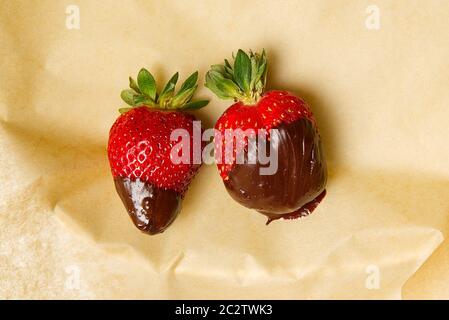 Zwei frische Erdbeeren in Schokolade auf Backpapier. Lecker. Stockfoto