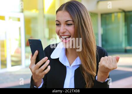 Erfolgreiche Geschäftsfrau lesen gute Nachrichten auf dem Smartphone und Feiern freuen. Stockfoto