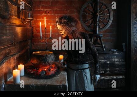 Beängstigend Hexe liest Bann über den Topf, dunklen Mächte der Hexerei, spirituelle Seance mit Kerzen. Weibliche foreteller ruft die Geister, schreckliche Zukunft t Stockfoto