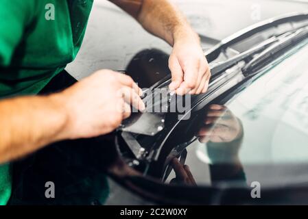 Arbeiter Hände installiert Auto lack Schutzfolie auf der Motorhaube. Transparente Schutzschicht vor Kratzern und Schrammen Stockfoto