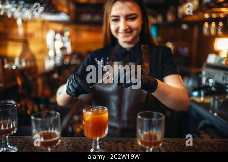 Weibliche Barkeeper Holding ein Glas mit Cocktail über die Theke. Alkohol Vorbereitung. Barkeeper in Pub arbeiten Stockfoto