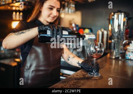 Weibliche Barkeeper gießt Rotwein in ein Glas. Frau Barkeeper an der Theke im Pub. Barkeeper Besetzung Stockfoto