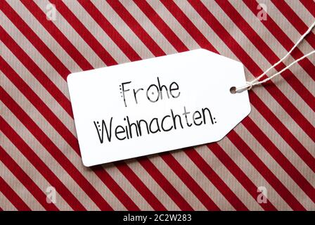 Etikett mit Deutschen Kalligraphie Frohe Weihnachten, Frohe Weihnachten. Rote Verpackung Papier als Hintergrund Stockfoto