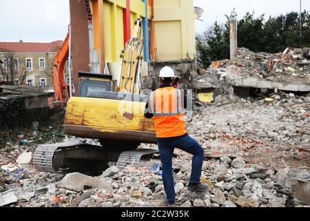 Ingenieur mans in Helm und Jacke Kontrolle Außenbaustelle. Ingenieur Mann beobachten Maschinen auf Abbruchstelle. Stockfoto