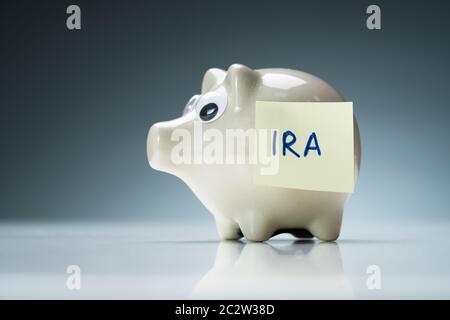 Eine weiße Sparschwein auf eine reflektierende Schreibtisch mit Ira Text auf Kleber Hinweis Stockfoto