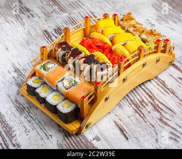 Große Menge japanischer Brötchen auf Holzservierbrett, dekoriert mit Zitrone, Wasabi, Ingwer und Isabi. Restaurantpräsentation von Speisen. Stockfoto