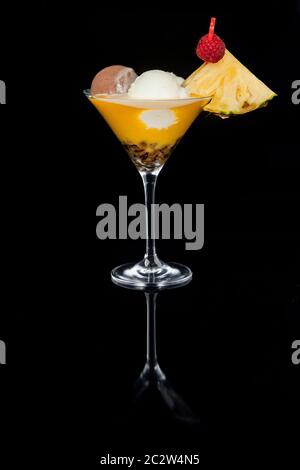 Großes Eis-Dessert mit Joghurt, Obst und Schlagsahne auf schwarzem Hintergrund. Ein Glas mit Spiegelreflexion. Katalogbild Stockfoto