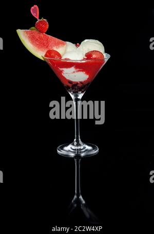 Großes Eis-Dessert mit Joghurt, Obst und Schlagsahne auf schwarzem Hintergrund. Ein Glas mit Spiegelreflexion. Katalogbild Stockfoto