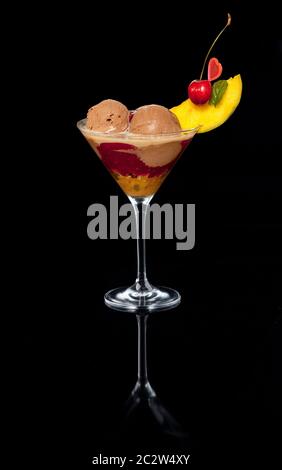 Großes Eis-Dessert mit Joghurt, Obst und Schlagsahne auf schwarzem Hintergrund. Ein Glas mit Spiegelreflexion. Katalogbild Stockfoto