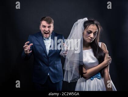 Braut mit weinerlicher Gesicht und schrecklich brutalen Bräutigam Anzug, Studio-Foto-Shooting, schwarzer Hintergrund. Stockfoto