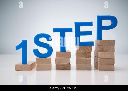 1. Schritt Buchstaben auf Schritte über grauer Hintergrund Stockfoto