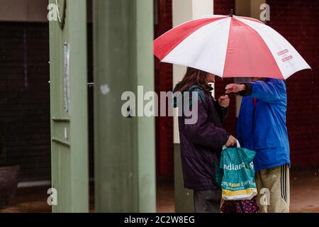 MERTHYR TYDFIL, WALES - 18. JUNI 2020: In einem verlassenen Einkaufszentrum, das aufgrund der Coronavirus-Pandemie geschlossen wurde, schützen die Käufer mit Regenschirmen vor dem starken Regen. Foto: John Smith / Alamy Live News Stockfoto