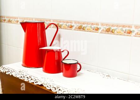 Rote Tasse und zwei Teekannen auf dem Tisch in der Küche Stockfoto