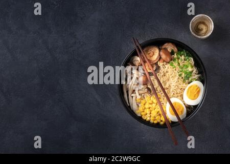 Ramen. Soba Nudeln mit Ei, Shiitake und Enoki-Pilzen, Mais und Schalotten, von oben auf dunklem Grund mit Cho geschossen Stockfoto