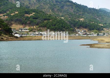 Landschaft auf dem Land, Nordkorea. Dorf am Flussufer Stockfoto