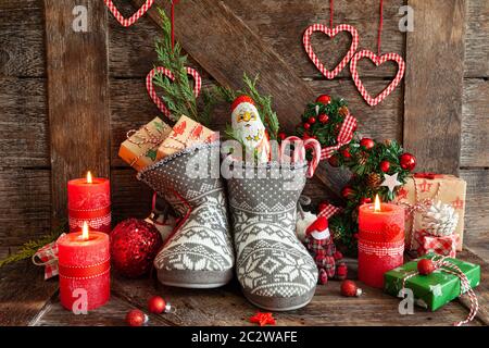 Gestrickte Stiefel mit kleine Geschenke und Süßigkeiten für Weihnachten Stockfoto