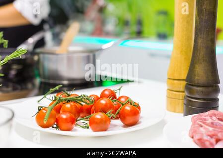 Nahaufnahme der verschiedenen Zutaten auf dem Tisch, Kirschtomaten im Vordergrund Stockfoto