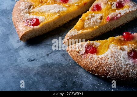 Nahaufnahme einiger Stücke einer Coca de Sant Joan, ein typischer süßer flacher Kuchen aus Katalonien, Spanien, gegessen an der St. Johns Eva, auf einer grauen Steinoberfläche Stockfoto