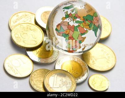 Weltkugel und verschiedene Münzen Stockfoto