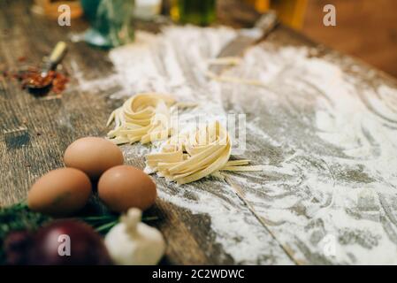 Zutaten zum Kochen von hausgemachten Nudeln auf hölzernen Küchentisch mit Mehl bestreut closeup, niemand. Fettuccine Vorbereitung Stockfoto