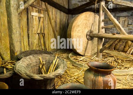 Nahaufnahme des hölzernen Geräte, Instrumente und Stroh in der Scheune. Mühlstein Interieur Stockfoto