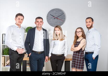 Lächelnde Mitarbeiter stehen und sehen aus, wie sie im Büro ein Teambild machen. Business People Team. Erfolgreiche Firma mit Stockfoto