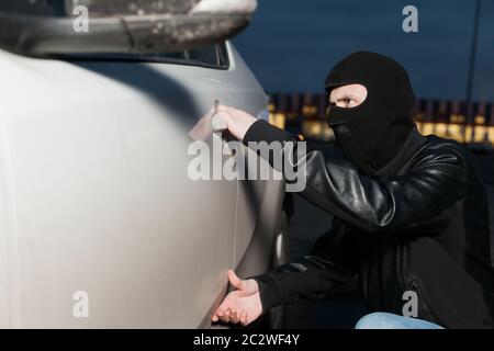 Männliche Dieb mit Haube auf dem Kopf, die Autotür öffnen möchten. Carjacker Fahrzeug entriegeln Stockfoto